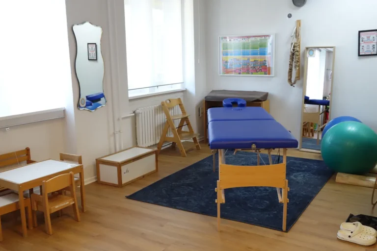 Therapieraum mit Behandlungsliege, Gymnastikball und Kindertisch